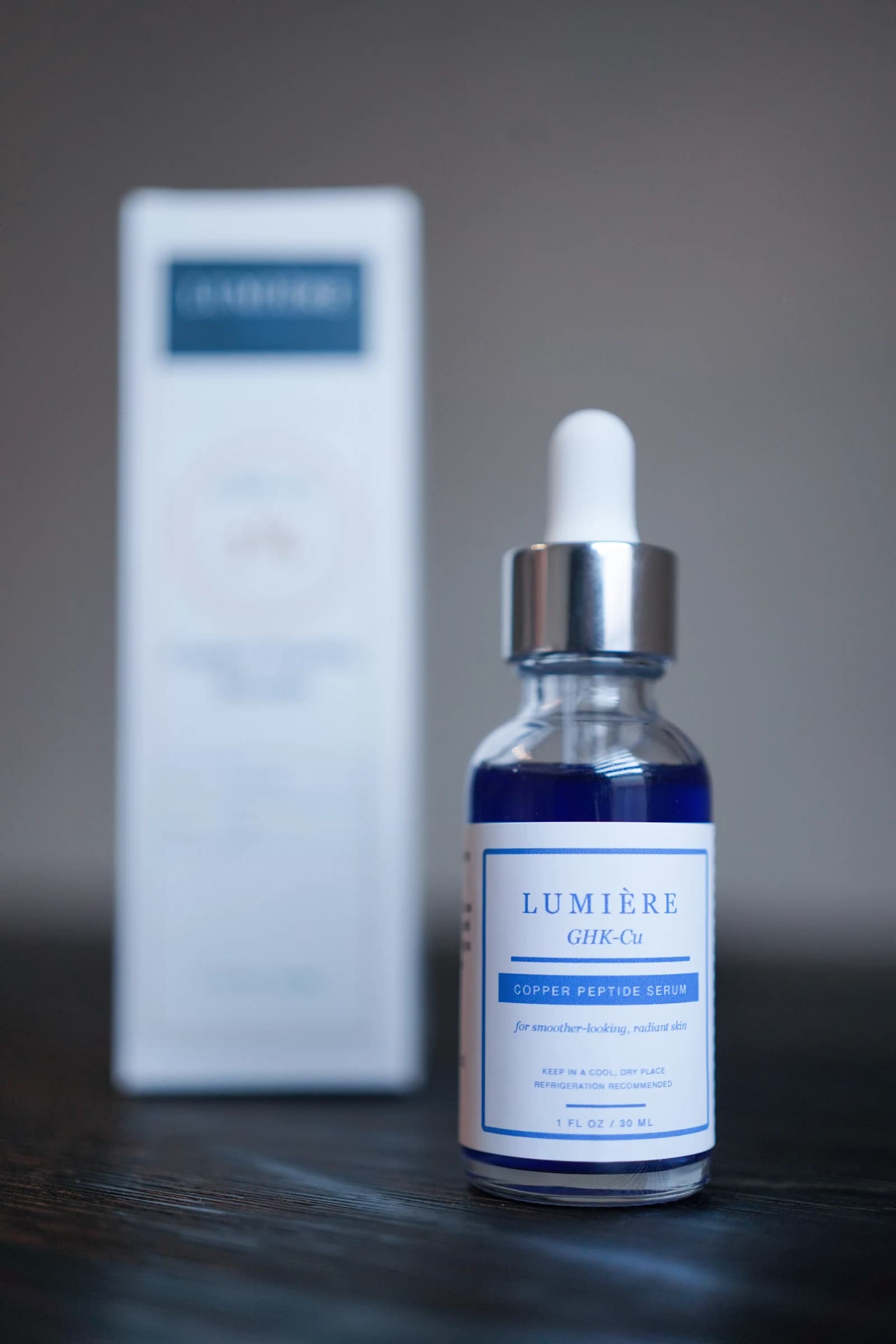 The complete GHK-Cu serum bottle and carton against a quiet studio backdrop